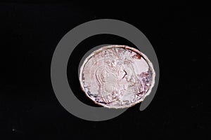 Close of a silver coin engraved with images of kuberan photo