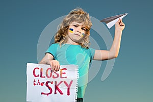 Close the sky over Ukraine banner. No fly zone over Ukraine. Ukraine flag on kids cheek. Military ukrainian aircraft.