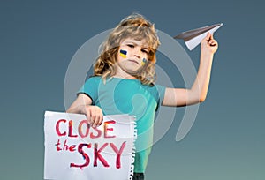 Close the sky over Ukraine banner. No fly zone over Ukraine. Ukraine flag on kids cheek. Military ukrainian aircraft.