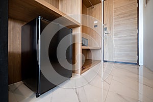 Close small refrigerator under the wood counter and in front of enter door delux room at resort and hotel