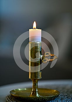 close to small candle in candlestick made of brass