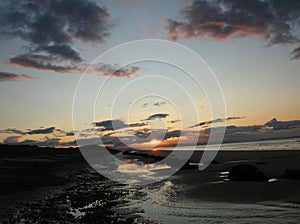 Evening sky with dark rainclouds and fiery sunlight reflections at Findhorn Bay, Scotland