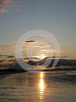 Evening sky with dark rainclouds and fiery sunlight reflections at Findhorn Bay, Scotland photo