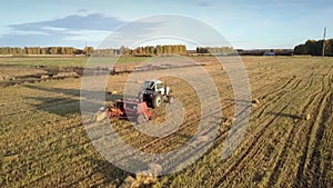 Close tractor drives baler pushes up straw bale on field