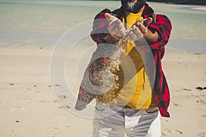 Close u view of unrecognizable caucasian tourist man playing with the sand at the beach durint tropical vacation - adult people