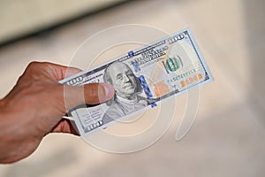 Close up 100 Dollar bank note in hand on grass background. One hundred American dollars.