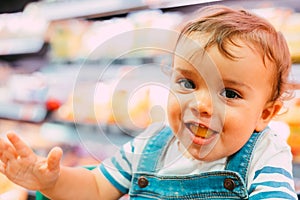 Close-up of 18-month-old child in supermarket with unfocused background and eating bread