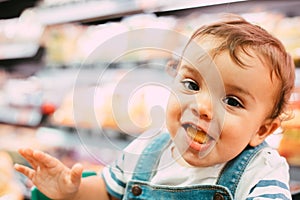 Close-up of 18-month-old child in supermarket with unfocused background and eating bread