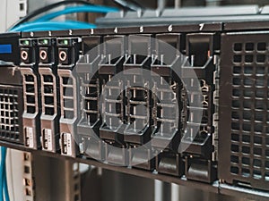 Close up of 2.5 inches hard drives bay in front of a working rack server installed in the server room to store information .