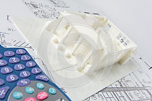 Close-up of 3D model of the house printed on a 3D printer and calculator.