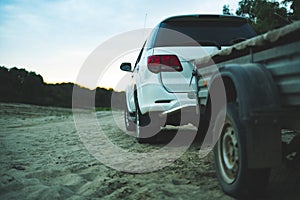 Close up 4x4 off road car vehicle standing on the sandy surface in beach with trailer d