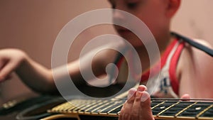 Close-up of a 5-7 year old Caucasian boy playing the guitar at home. Shallow depth of field,