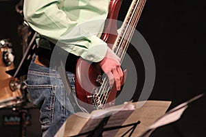 Close-up of a 5-string bass guitar. The sides are struck by the musician. Electric Bass in a Big Band. Bassist playing music. Bass