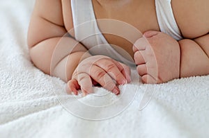 Close up of a 6-month-old Asian baby`s  hand under the chest in the tummy time position.
