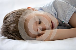 Close up 7s Caucasian boy sleeping on cozy bed