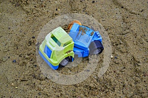 Close-up of an abandoned children's blue-green plastic toy truck inside a sand pit, a children's playground.