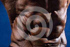 Close-up of abdominal muscles bodybuilder on a blue background