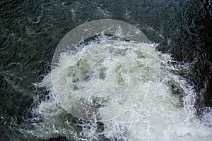 Close-up abstract texture above view of river torrent and clear fresh cold water flowing through mountain rocks in valley with