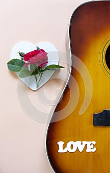 Close up of Acoustic guitar with beautiful blossoming rose flower and word Love