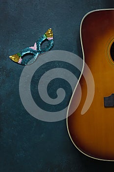 Close up of acoustic guitar and carnival mask on blue background