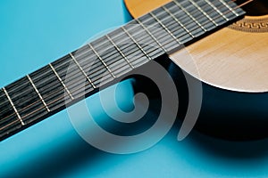 Close-up of acoustic guitar neck on blue background