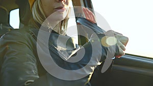 Close-up of action girl fastens a seat belt in a car before dropping off. Safe driving concept