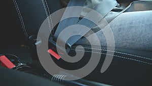 Close-up of action girl fastens a seat belt in a car before dropping off. Safe driving concept