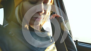 Close-up of action girl fastens a seat belt in a car before dropping off. Safe driving concept
