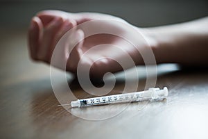 Close up of addict hand and used drug syringe