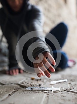 Close up of addict woman reaching to drug syringes