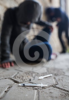 Close up of addicts and drug syringes on ground