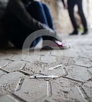 Close up of addicts and drug syringes on ground