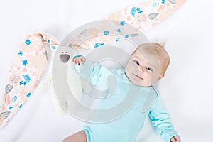 Close-up of adorable cute newborn baby girl of two months on white background. Lovely child playing with plush rabbit