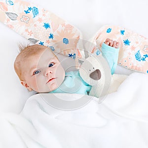 Close-up of adorable cute newborn baby girl of two months on white background. Lovely child playing with plush rabbit