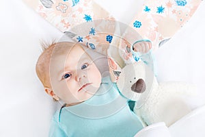Close-up of adorable cute newborn baby girl of two months on white background. Lovely child playing with plush rabbit