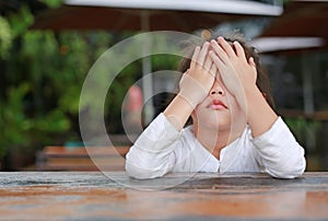 Close-up of adorable little Asian child girl expressed disappointment or displeasure on the wood table photo