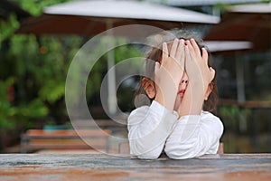 Close-up of adorable little Asian child girl expressed disappointment or displeasure on the wood table