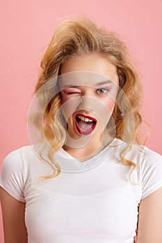 Close-up adorable pretty young girl with bright makeup and hairdo in retro 90s fashion style isolated over pink studio