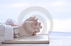 Close up of adult female hands praying on open Holy Bible page with outdoor softly bright light background