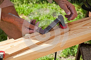 Close-up of adult male hands holding woodworking marking tool - red pencil and metal ruler corner and measures and marks the area