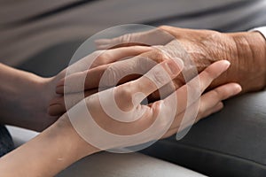 Close up of adult mom and daughter holding hands