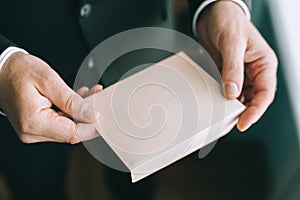 Close up of adult serious man's hands holding a white envelope without inscriptions