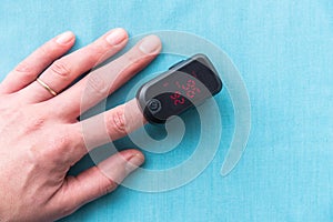 Close-up of adult woman`s hand wearing pulse oximeter to measure blood oxygen saturation