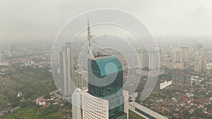 Close up aerial dolly shot of the top of Wisma 46 skyscraper in Jakarta, Indonesia on a cloudy day