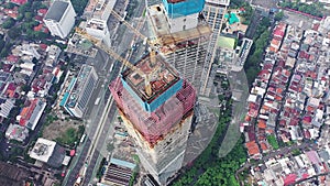 Close up aerial view of crane lowering an object on the roof of the skyscraper under construction in Jakarta, Indonesia