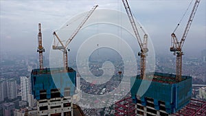 Close up aerial view of crane lowering an object on the roof of the skyscraper under construction in Jakarta, Indonesia