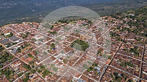 Close-up aerial view of historic town Barichara, Colombia situated on a cliff edge, in the center green plaza and cathedral