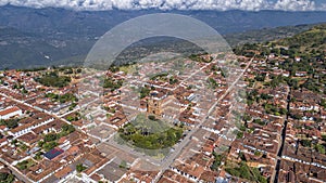 Close-up aerial view of historic town Barichara, Colombia situated on a cliff edge, in the center green plaza and cathedral