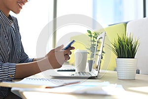 Close-up of african american business woman hands using mobile while sitting in modern office