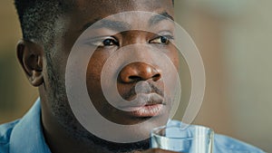 Close up African American ethnic man thoughtful businessman drink glass water take break drinking still liquid aqua